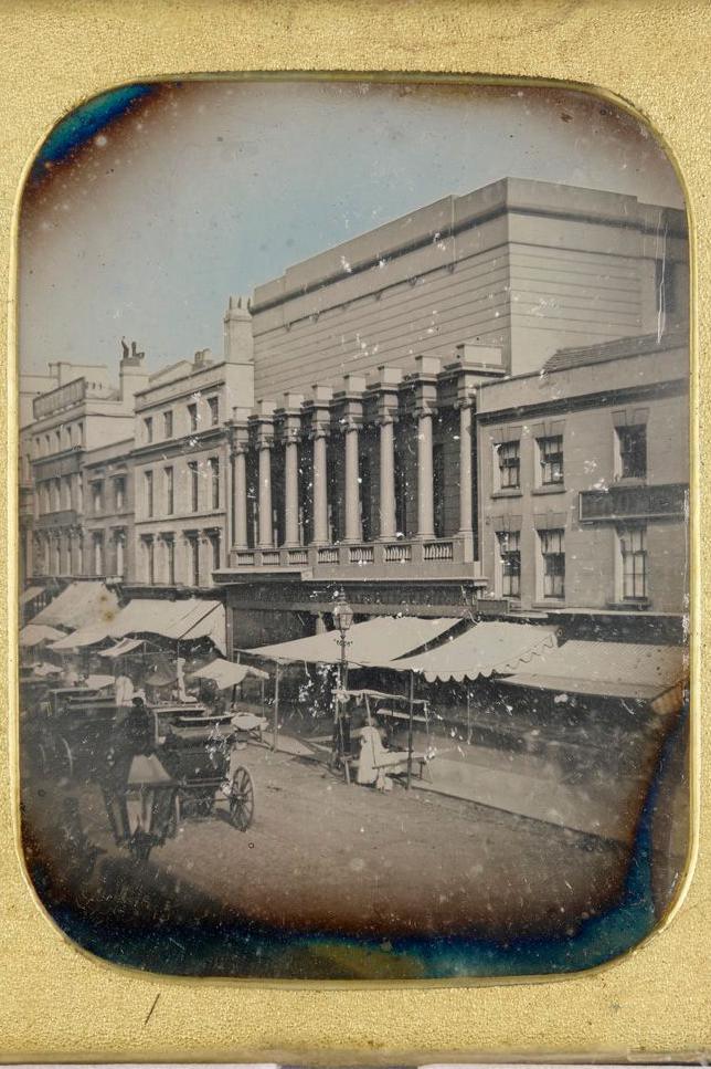 A black and white image of New Street captured on a daguerreotype, it shows shop frontages with canopies as well as horses and carts