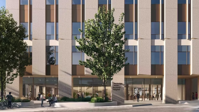 A CGI image of what the new cancer hospital will look like.It is tall and has different brown blocks and panels on its front, as well as many windows. There is a tree in front of the building and people are sat or walking around.