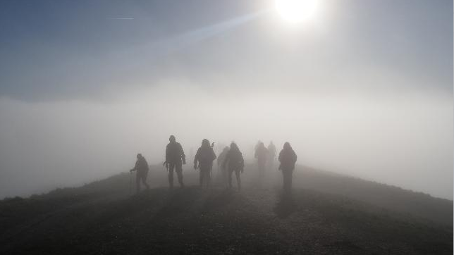 Walkers on the hills are seen in mist and fog and some sunshine on Saturday. The group look to be wearing outdoor gear and are seen in silhouette against the sun.