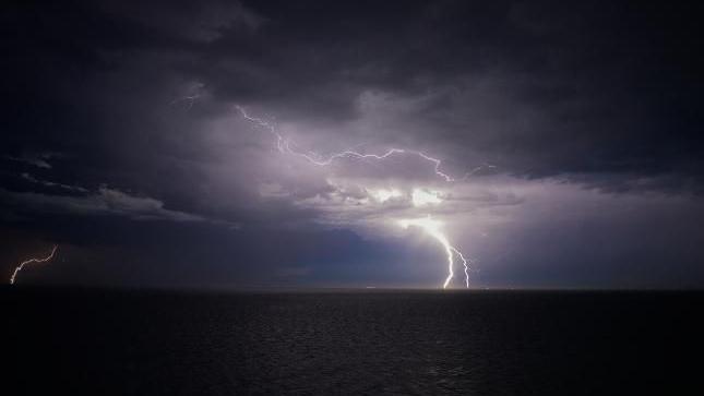 Lightning strikes at night out at sea.