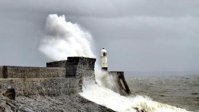 Waves hitting the sea wall at Porthcawl in Bridgend county against a grey sky