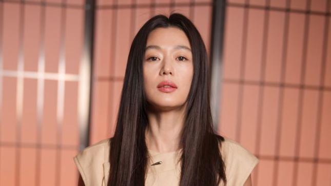 Jun Ji-hyun in a beige dress standing in front of a pink background
