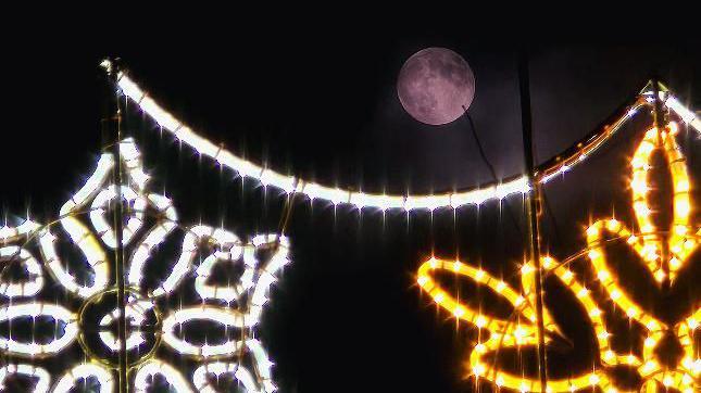 A closeup of the moon behind some christmas decorations.