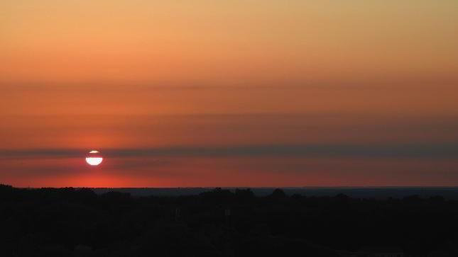 the sky with the sun setting in the left corner