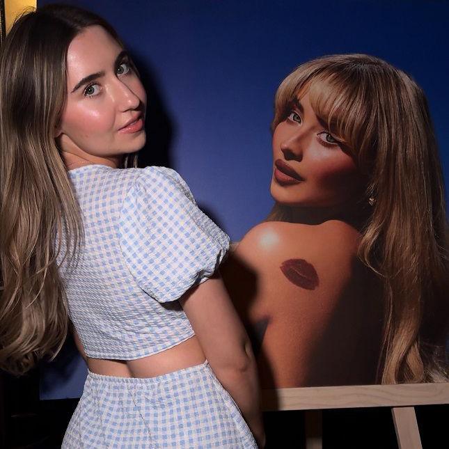 Sabrina Carpenter fan Amy posing alongside a poster of the star
