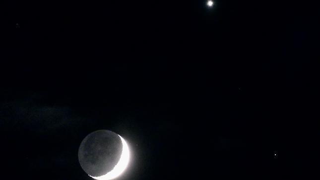 A crescent moon and Venus against a black sky