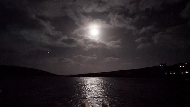 The moon is just about visible in a cloudy night sky.