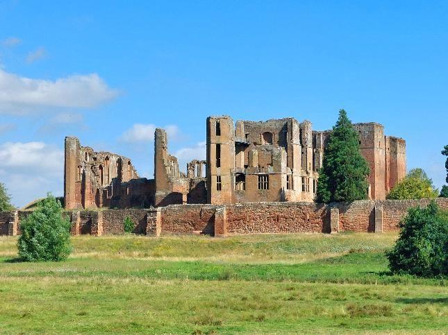 A ruined castle in the distance, surrounded by trees and grass 