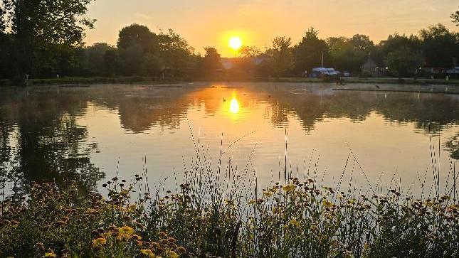 The sun sets over a lake in East Horsley