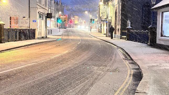 Okehampton high street seen with a frosyy road and traffic lights glaring green in the distance