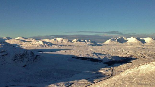 The mountain of An Teallach on the right and mountains of an area known as the Last Great Wilderness. The landscape is covered in snow.