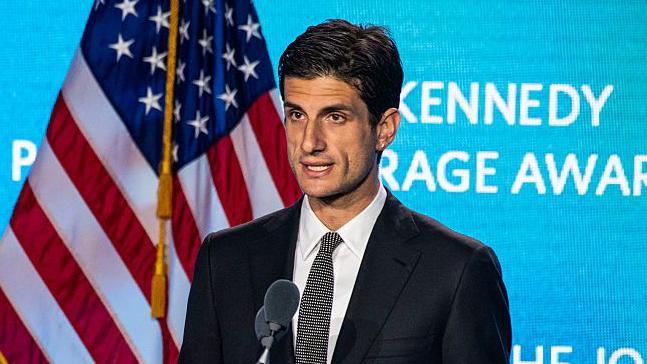 Jack Schlossberg speaks into a podium in front of an American flag during the 2025 John F. Kennedy Profile in Courage Award Ceremony.