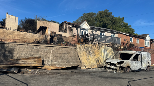 Burnt out houses and a burnt out car.