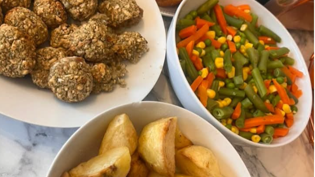 Dishes of roast potatoes, vegetables, stuffing and Yorkshire puddings can be seen on a table