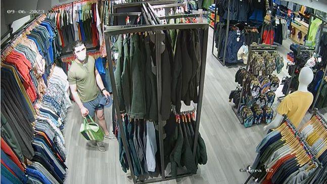 Daniel Khalife, pictured in a face mask, a green t-shirt and blue shorts, is pictured in the men's clothing section of a Mountain Warehouse store in a shot from CCTV footage