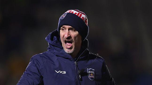 Alan Dickens, wearing a big coat and a woolly hat, shouting at his players