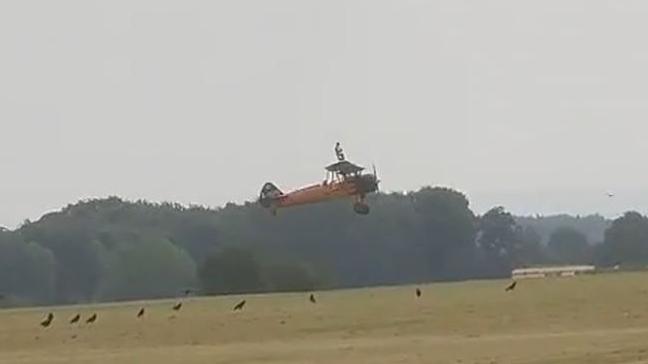 A view of a man standing on a plane while it is in flight