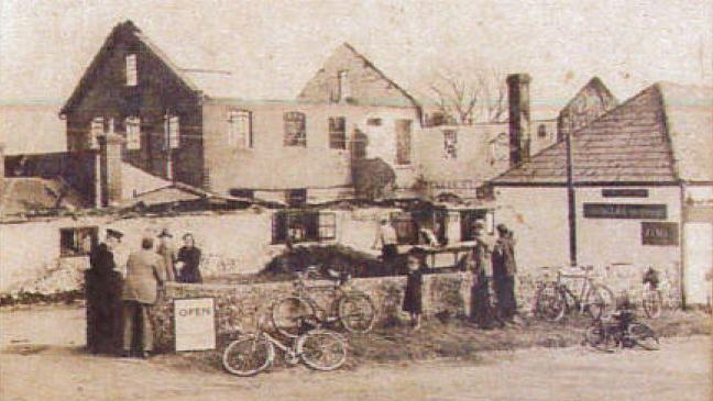 A  black and white image of destroyed buildings at Drusillas. Multiple bicycles lay next to a stone brick wall in the foreground.