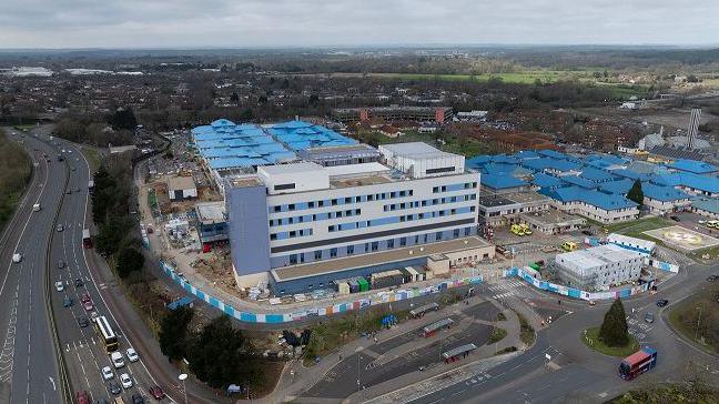 An aerial photo of Royal Bournemouth Hospital, a site with multiple buildings with blue roofs. Part of it looks to be a construction site