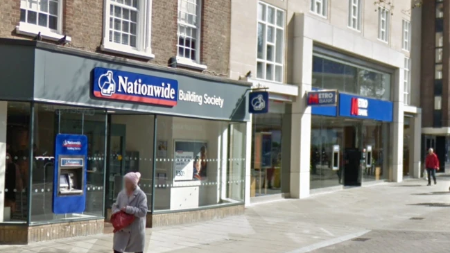 The Nationwide Building Society branch in Peterborough city centre. It is in a pedestrianised street and has a glass front. It is next to a Metro bank.