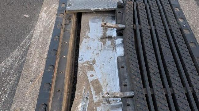 A close-up photo of a damaged metal joint along a motorway. The metal of the joint has been taken away and several parts are sticking out.