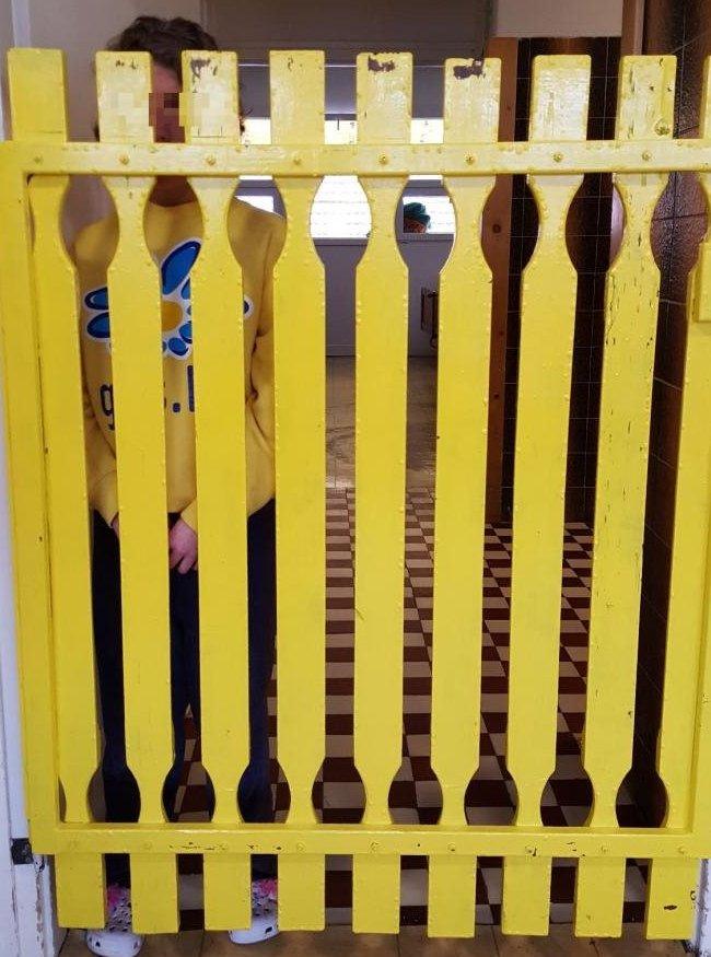 A young woman on Female Ward A behind a wooden fence.