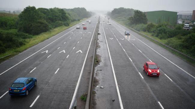 An overhead shot of two motorway lanes on the M4 with several cars driving on the carriageways.