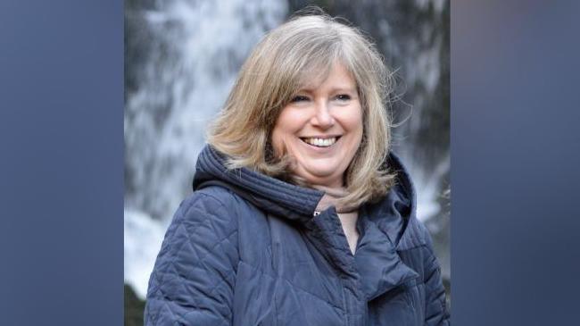 Susan Baird standing in front of a waterfall 