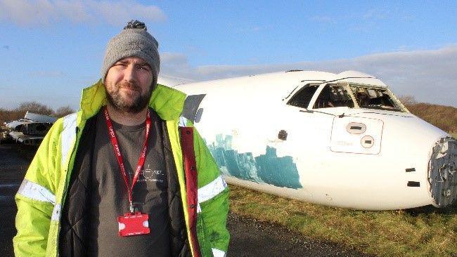 Stuart Abbott standing in front of the plane's fuselage