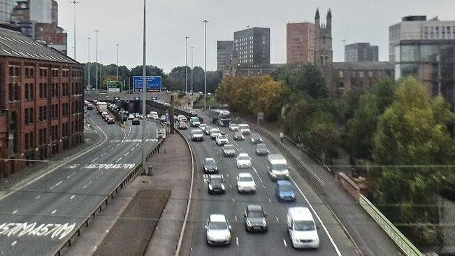 Afternoon traffic passes over a bridge on Dawson Street in Manchester. Trees can be seen on one side of the street - with 