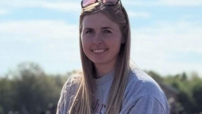 Jennie Logan looking at the camera and smiling. She is wearing a grey sweater and has sunglasses on top of her head.
