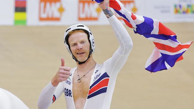 Stephen Bate celebrates by holding up a British flag behind pilot Christopher Latham