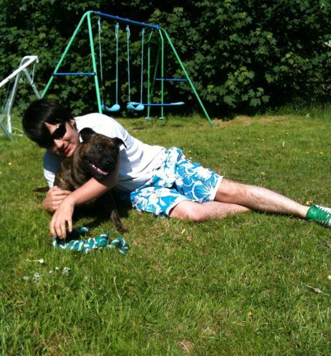 Warren Fenty lying on the grass holding a dog