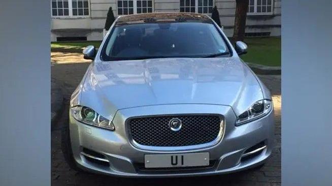A silver sports car bearing the number plate 'UI'