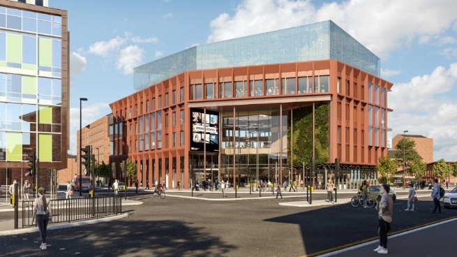 Large building with orange bricks on corner of busy road junction