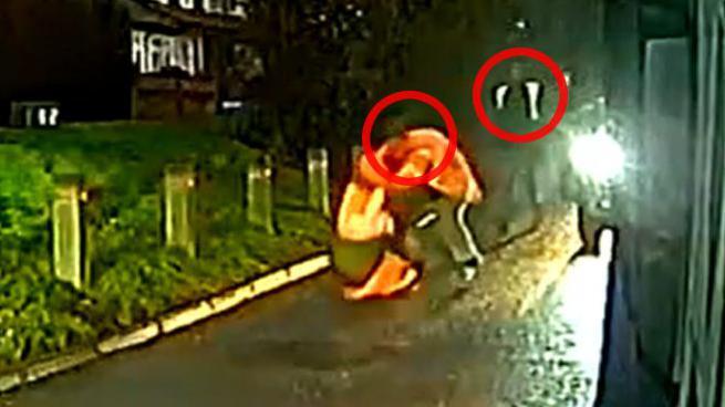 Blurred CCTV footage of a scuffle on the edge of a road, captured on a bin lorry's camera.