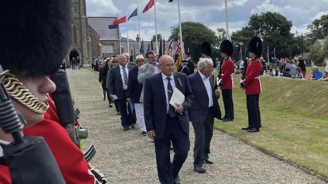 A group of people holding petitions walking down the ceremonial walkway to Tynwald Hill