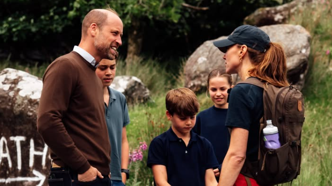William looks at Kate as they talk while the three kids stand in the background