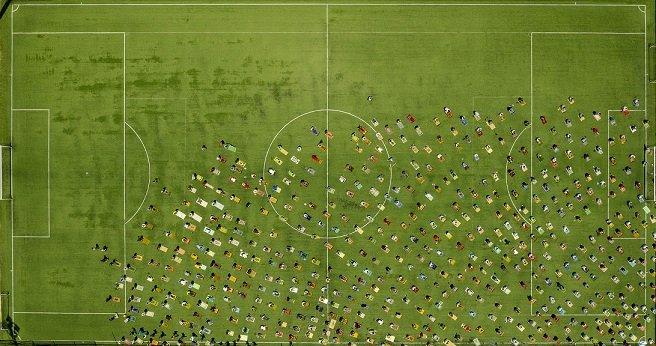 many people praying on football pitch