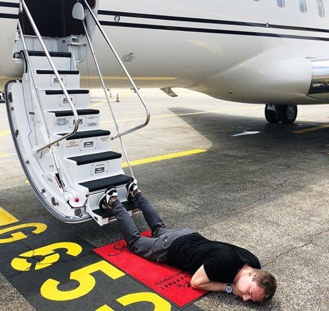 A man lying on a runway his legs strewn on the steps of a private jet