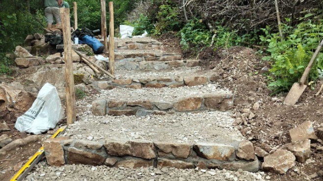 Gorge Walk improvements at Cheddar Gorge showing new steps up a slope being constructed from rock and wood