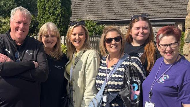 Six people are looking at the camera and smiling. Maria Hanson is standing second from the left.