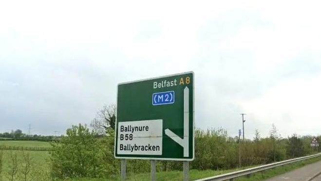 A green road sign which shows a left turn leading to Ballynure B58 Ballybracken and straight to Belfast A8. 