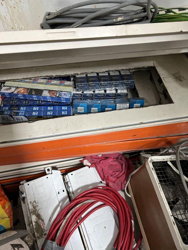 Multiple packets of tobacco products hidden. Wires and electrical equipment surround them.