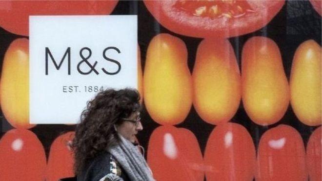 Woman walks by M&S storefront