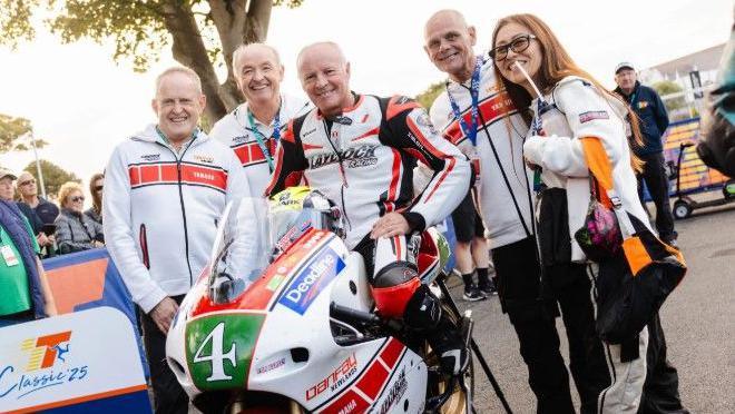 Ian Lougher in white, red and black leathers sitting on a motorcycle with the same colours that has the number 4 on a green plate on the front.