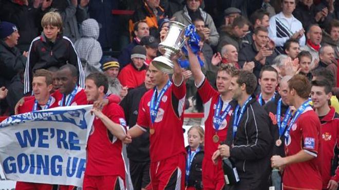 Kettering Town players in red, black and white home shirts celebrate winning the Blue Square North title at Rockingham Road in 2008. 