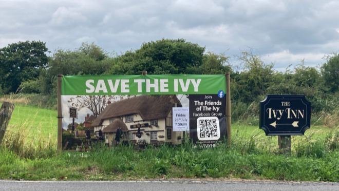 A banner on a country road reading 'Save the Ivy' 