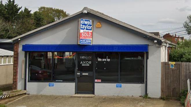 An empty shop with a large window and a "sold" sign.