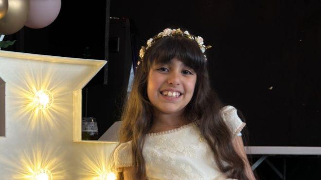 Alice da Silva Aguiar pictured during her Holy Communion, she is wearing a white dress and smiling for the camera